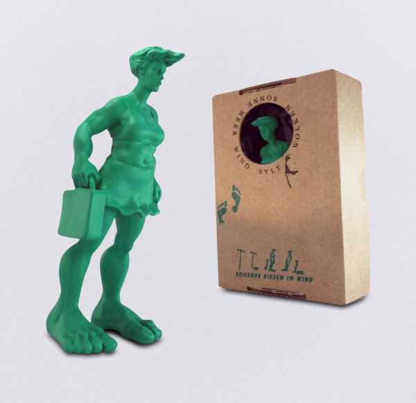 Miniatur der grünen Sylter Riesin 10 cm, mit Beispielverpackung im Karton. Aus der Skulpurengruppe: Reisende Riesen im Wind vom Künstler Martin Wolke.
