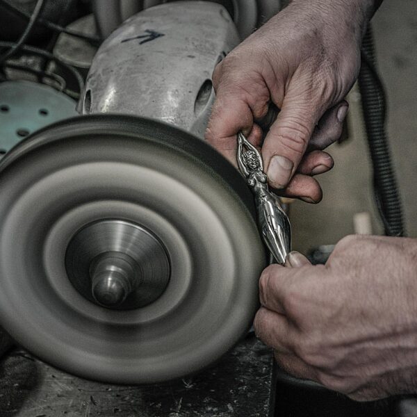 Polishing a pewter bottle cap on the polishing machine. Bottle mermaid by Neptune jewelry.