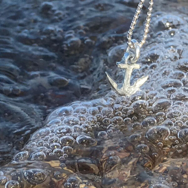 El colgante de ancla se sumerge en el rocío en una cadena de plata. De Neptuno Joyas.