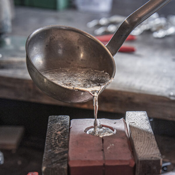 Despejando estanho derretido em um molde de silicone. Das joias de Netuno.