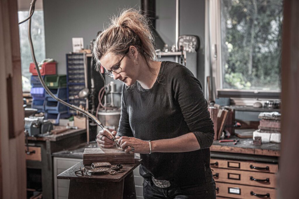 Neptunsgeschmeide Werkstatt. Jen Wolke entgratet eine Gürtelschnalle per Hand.