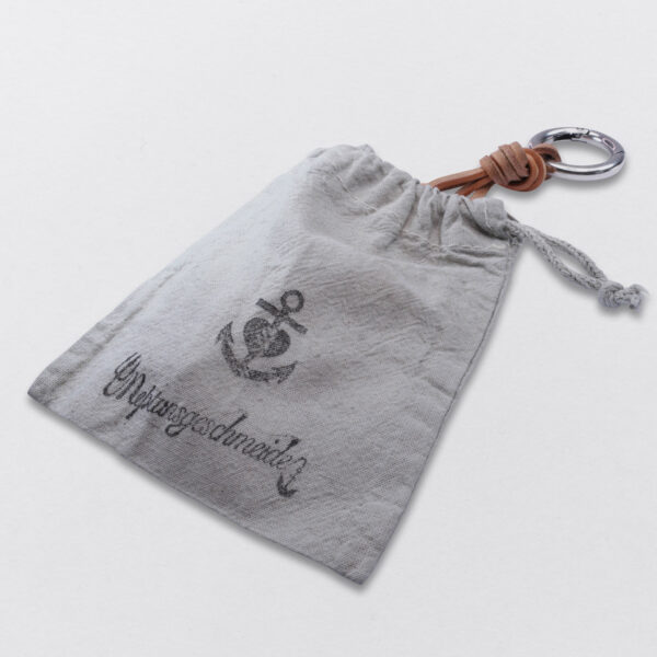 Verpackung eines Gebamsel® Schlüssel und Taschenschmucks in einem hand gestempelten Baumwollbeutel von Neptunsgeschmeide.