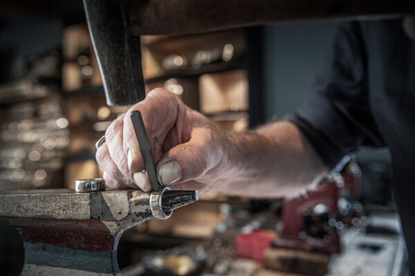 Neptune jewelry workshop: production of a band ring embossed with the text Hope. Hand embossing.