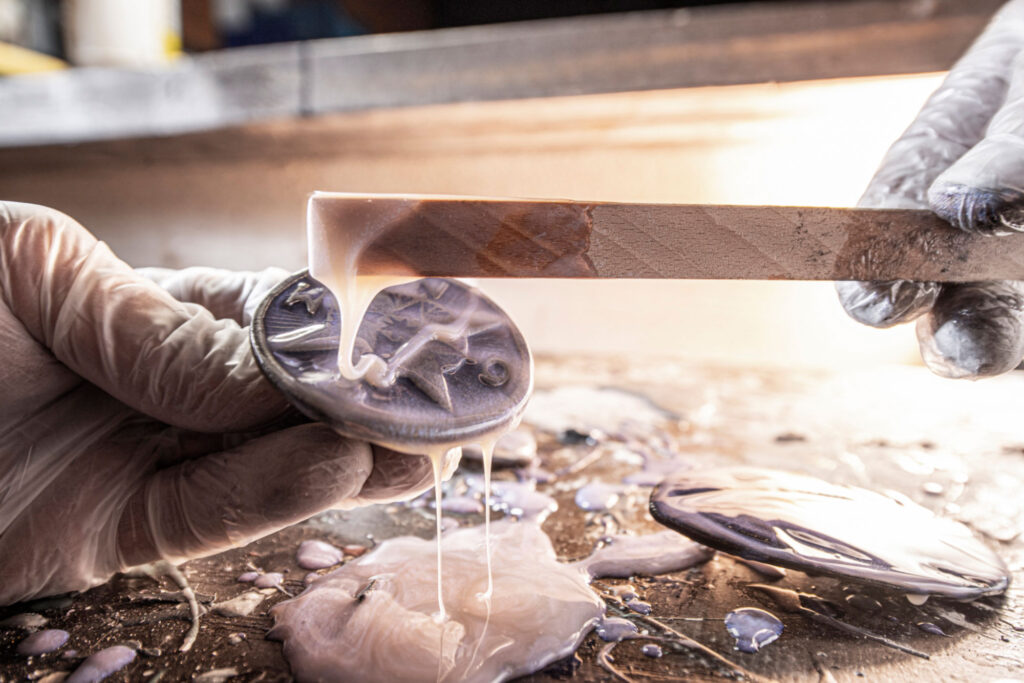 Neptunsgeschmeide Werkstatt. Herstellung einer Gürtelschnalle, Motiv Kompass. Veredelung mit Gießharz von Hand.