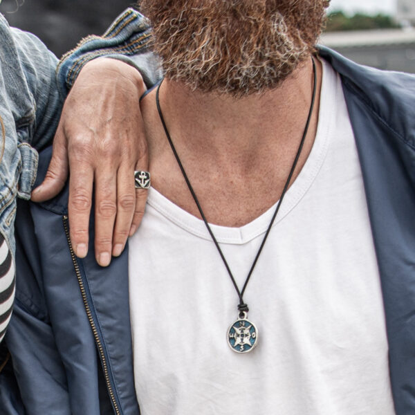 Collier boussole sur bracelet cuir. sur le bracelet en cuir noir rond de 2 mm de NeptunsSchmeiße. Taille du pendentif : environ 3 cm de diamètre. Photo promotionnelle homme.