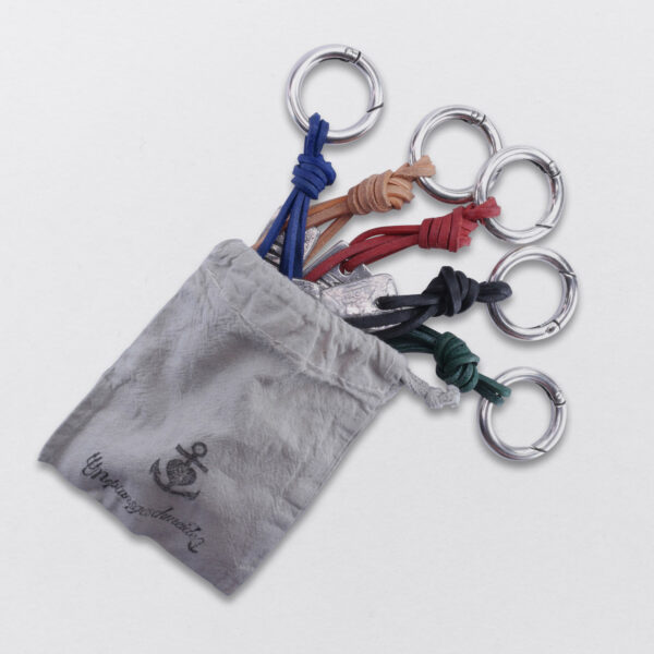 Verpackung von Gebamsel, Schlüssel und Taschenschmucks in einem von Hand gestempelten Baumwollbeutel von Neptunsgeschmeide.