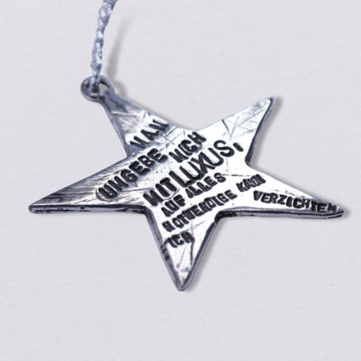 Weihnachtsstern Man umgebe mich mit Luxus...,Ein individualisierbarer Stern mit Wunschprägung als Weihnachtsbaumschmuck, hier mit einem Zitat von Oskar Wilde: man umgebe micht mit Luxus, auf alles notwendige kann ich verzichten. Handgeprägt von Neptunsgeschmeide. Maße: ca. 7 x 7 cm.