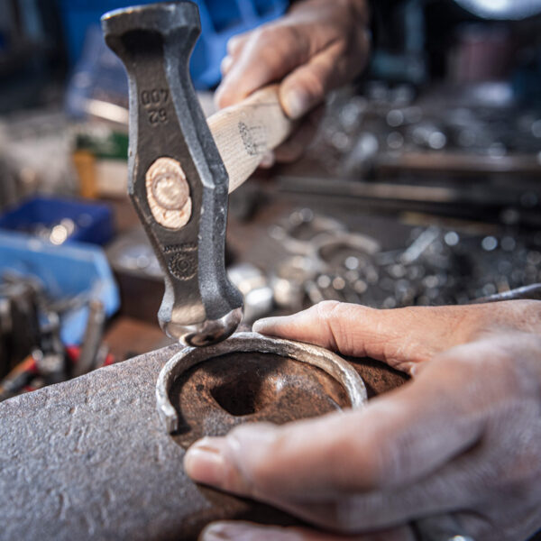 Produktion af et armring, overfladehamret, billede viser hammeren, der rammer armringen og skaber en bølgestruktur. Fra Neptune Jewels.