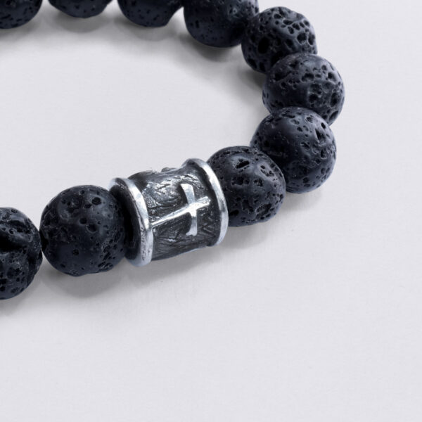 Armbånd Lava Beads Faith Love Hope. Fleksibelt armbånd og tinperle med prægede symboler. Detaljeret billede af krydsprægning, nærbillede.