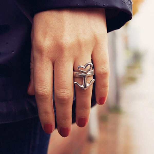 Motief ring hart anker vrijstaand, tin of zilver, handgemaakt door Neptune sieraden met optionele embossing aan de buitenkant. Gedetailleerd beeld van een motiefring aan de hand van een vrouw, close-up.