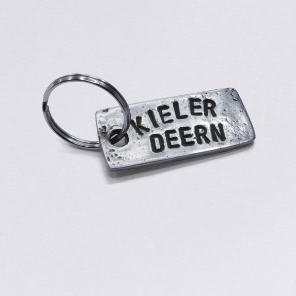 Key ring with embossing Kieler Deern, dimensions: approx. 2 x 4,5 cm, from NeptunsSchmeiße. Customizable with desired embossing.