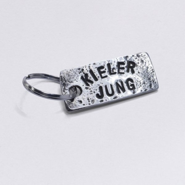 Key ring with embossing Kieler Jung, dimensions: approx. 2 x 4,5 cm, from NeptunsSchmeiße. Customizable with desired embossing.