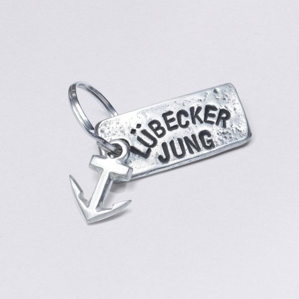 Key ring with embossing Lübecker Jung with a small anchor, dimensions: approx. 2 x 4,5 cm, from NeptunsSchmeide. Customizable with desired embossing.