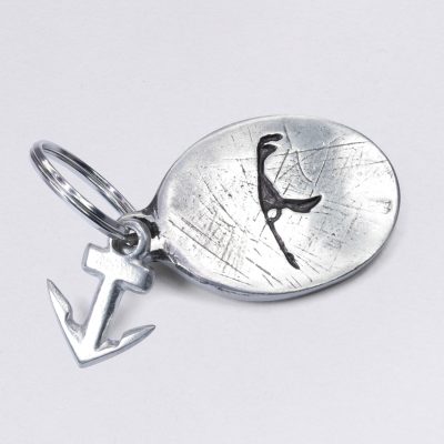Schlüsselanhänger mit Prägung Insel Sylt (Symbol) in oval, mit kleinem Anker, Zinn mit Einschlüssen, Maße: ca. 2 x 4,5 cm, von Neptunsgeschmeide. Individualisierbar mit Wunschprägung.