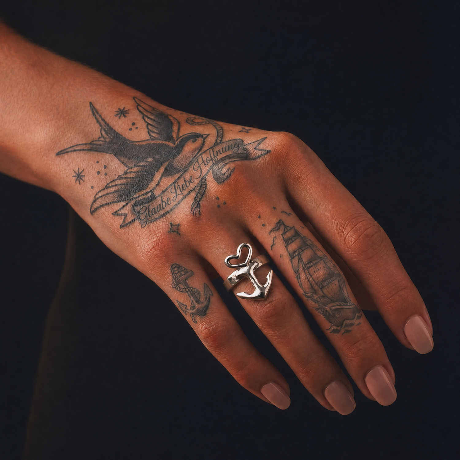 Motivring Herz Anker freistehend, Zinn oder Silber, Handarbeit von Neptunsgeschmeide. Detailbild Motivring an weiblicher Hand, Nahaufnahme.