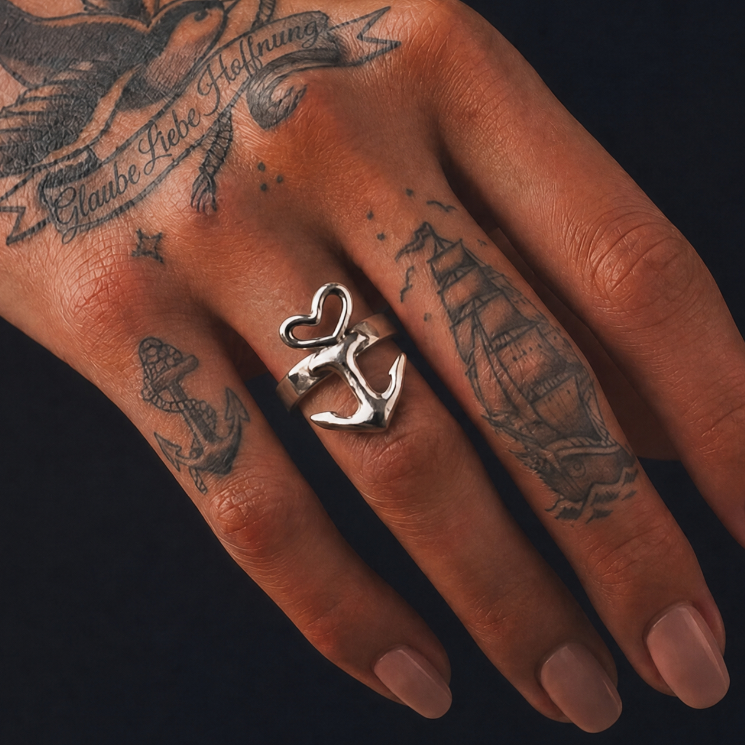 Motivring Herz Anker freistehend, Zinn oder Silber, Handarbeit von Neptunsgeschmeide. Detailbild Motivring an weiblicher Hand, Nahaufnahme.