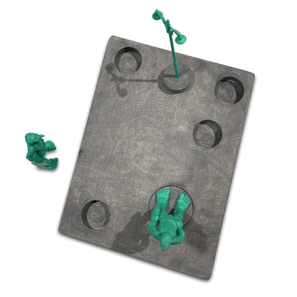 De runde utsparingene i en treplate gjør at individuelle miniatyrer av de grønne Sylt-gigantene kan settes inn som et samlesett.
