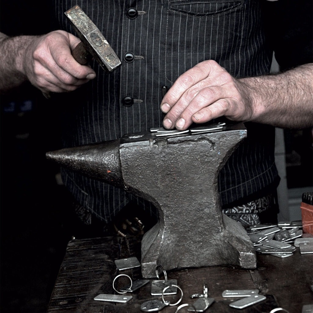 Schlüsselanhänger von Neptunsgeschmeide werden auf einem Amboss von Hand geprägt.