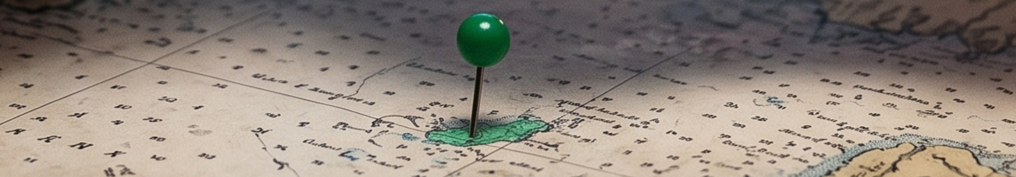 Koordinatenschmuck von Neptunsgeschmeide, zur Veranschaulichung steckt eine grüner Pin in einer Landkarte.