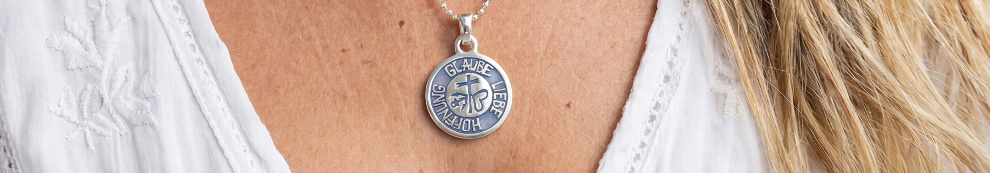 L'immagine della categoria mostra il ciondolo Fede - Amore - Speranza con riempimento in resina blu, realizzato in argento, indossato da una donna che nuota sott'acqua.